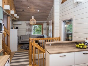 Et moderne køkken med trædetaljer, et spiseområde med en sofa og udsigt til grønne omgivelser.