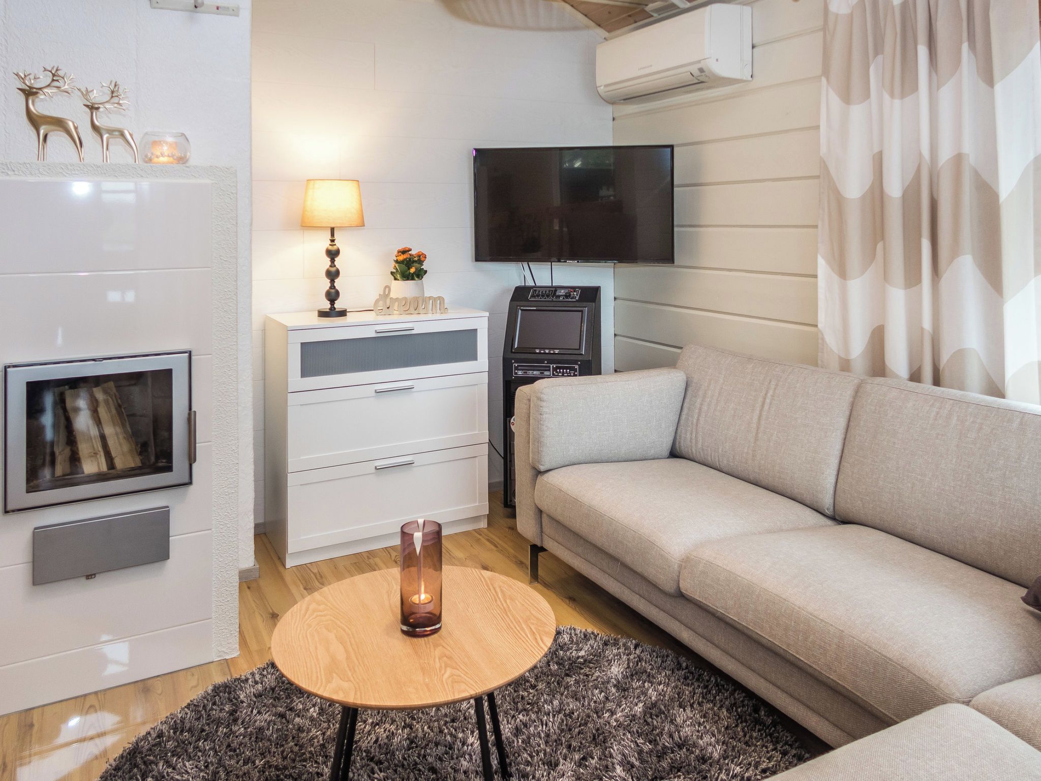 Una sala de estar moderna con un sofá, un televisor, una chimenea y una pequeña mesa con una vela.