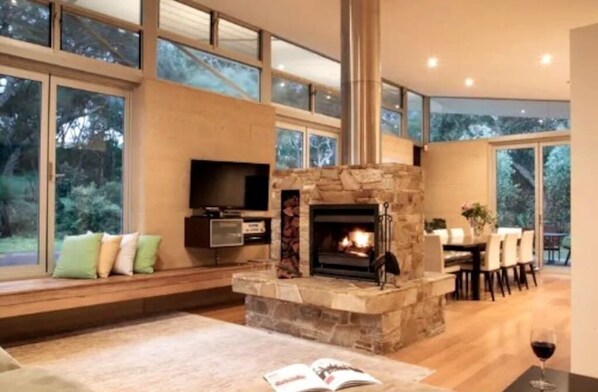 Relax in a serene space with a fireplace, large windows, and a comfortable sofa.