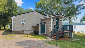 A small cabin with a porch and a staircase leading to a deck.