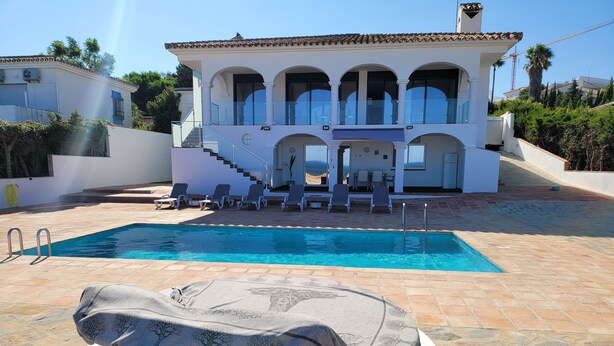 A pool area with a hot tub, lounge chairs, and a staircase leading to a building with multiple balconies. - luxury apartments sea views with pool (malaga)
