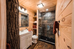 A wooden cabin bathroom with a shower, toilet, and vanity.