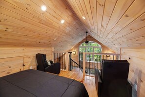 A wooden cabin interior with a loft bedroom, a staircase, and a view of the outdoors. - MoonLight Treehouse | Hot Tub · Lakefront Retreat (Belgrade)
