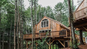 Une cabane en bois dotée d’un balcon, entourée d’arbres.