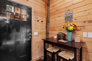 A wooden interior with a black door, a table with a vase of flowers, and a sign that reads 'Relax you're on Lake Time.' - MoonLight Treehouse | Hot Tub · Lakefront Retreat (Belgrade)