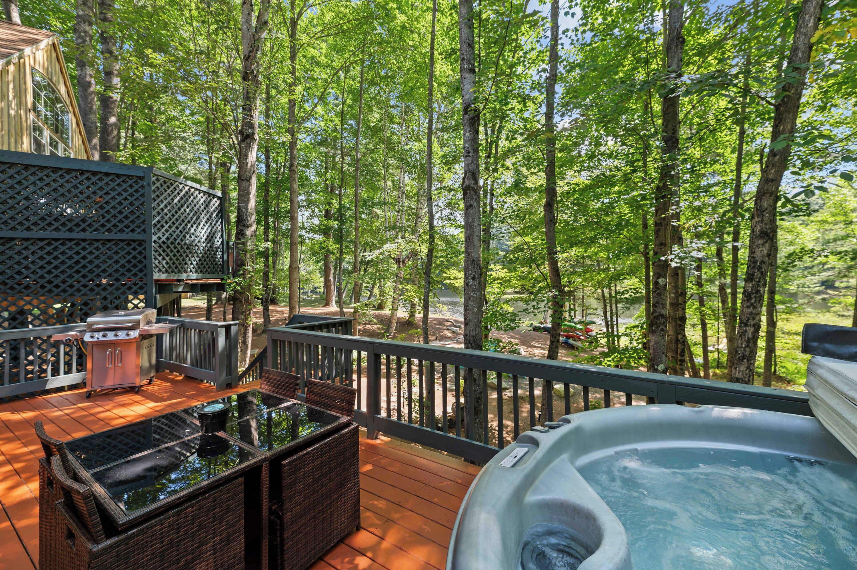 Een terras met buitenmeubilair, een hottub en uitzicht op een bebost gebied.