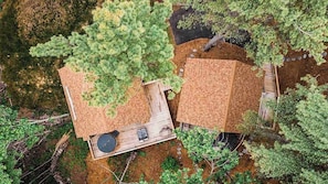 Two wooden cabins with attached decks, surrounded by dense forest.