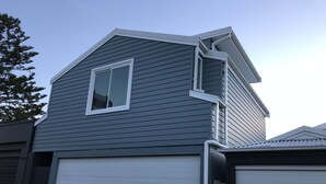 A two-story house with a garage door, a window, and a sloped roof. - Spacious Manly Studio (Fairlight)