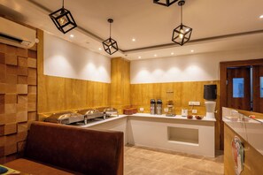 A modern kitchen with a buffet setup, wooden paneling, and pendant lighting. - Hotel Signature Airport zone hyderabad (Hyderabad)