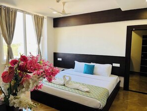 A hotel room with a bed, a ceiling fan, a window with curtains, and a vase with flowers. - Hotel Signature Airport zone hyderabad (Hyderabad)