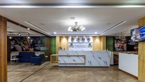 A hotel reception area with a marble reception desk, a blue sofa, and a wall-mounted television. - Hotel Signature Airport zone hyderabad (Hyderabad)