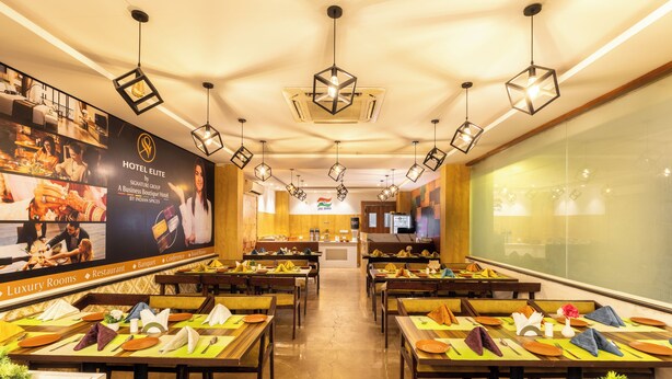 A hotel restaurant with multiple dining tables set with yellow tablecloths, wooden chairs, and neatly arranged cutlery. - Hotel Signature Airport zone hyderabad (Hyderabad)