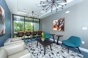 Relax in a stylish space with a sofa, chairs, and a small table, surrounded by a beautiful view of greenery.
