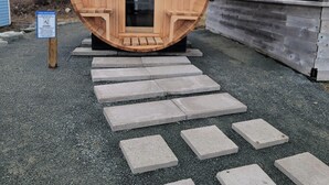 A wooden sauna with a glass door, a wooden bench inside, and a stone pathway leading to it. - Tangier Oceanfront Escape with Hot Tub, Sauna & Kayaks (Tangier)