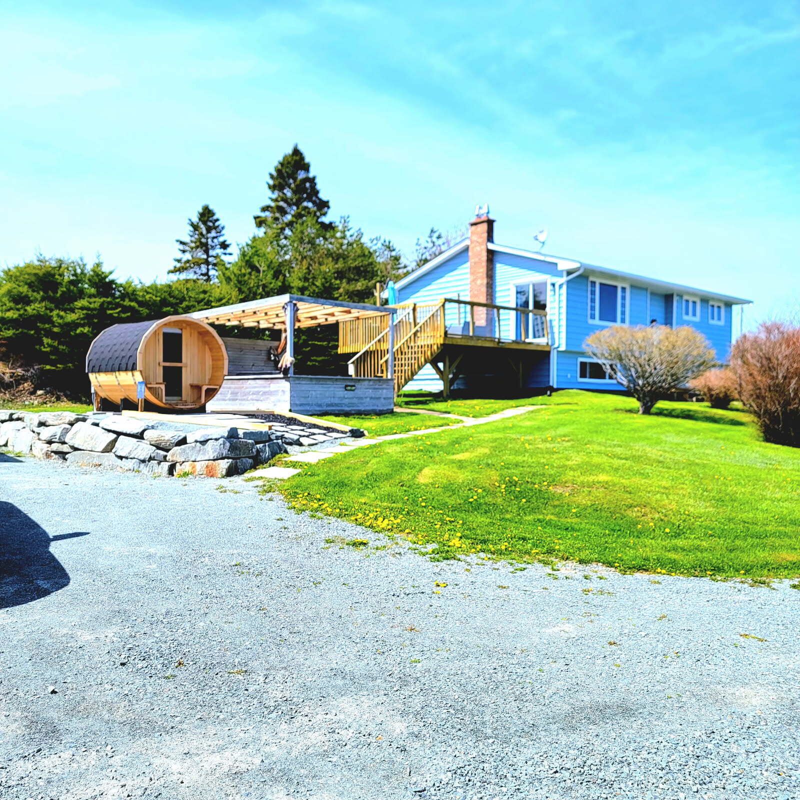 A house with a wooden cabin-like structure, a stone wall, and a well-maintained lawn.