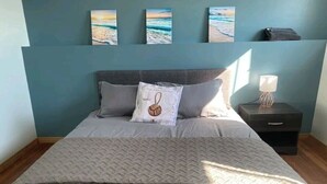 A bedroom with a bed, pillows, a nightstand, and wall art. - Tangier Oceanfront Escape with Hot Tub, Sauna & Kayaks (Tangier)