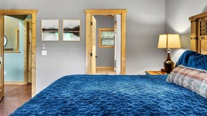 A bedroom with a large bed, wooden headboard, a nightstand with a lamp, and framed pictures on the wall. - New ModernRustic House in Smokys-4BR/Pools/Hot Tub/Billards/Games (Gatlinburg)