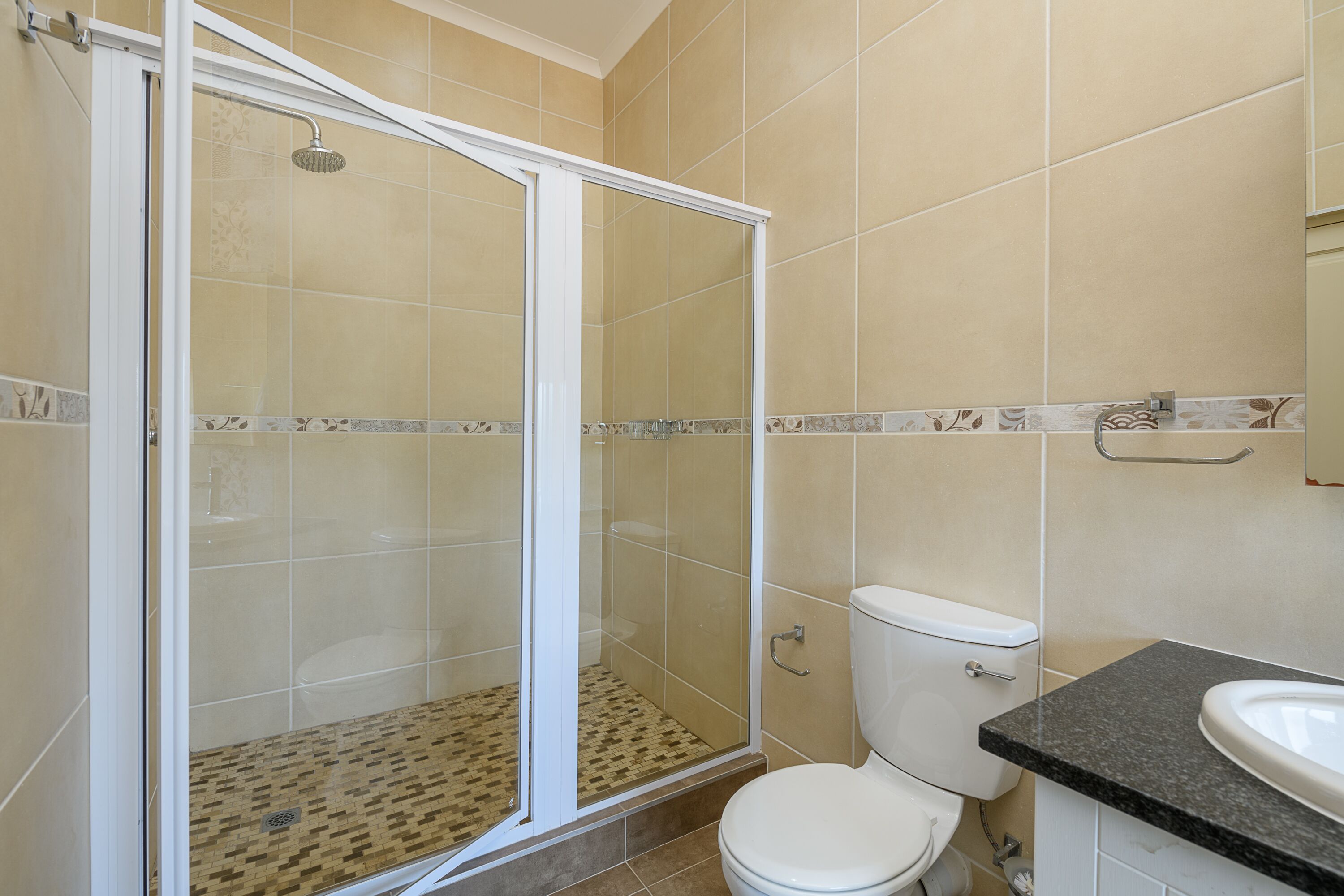 A bathroom with a shower, toilet, and sink.