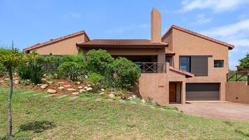 Enjoy the expansive front yard with a well-maintained lawn and lush plants from the balcony.