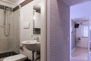 Une salle de bain moderne avec une douche à parois de verre, un lavabo blanc et un miroir.