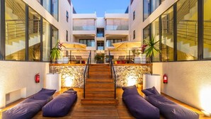 Ein modernes Hotel mit Atrium, einer Holztreppe, Sitzbereichen und großen Fenstern.