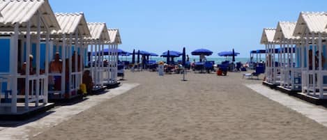 A beach with beach huts and umbrellas.