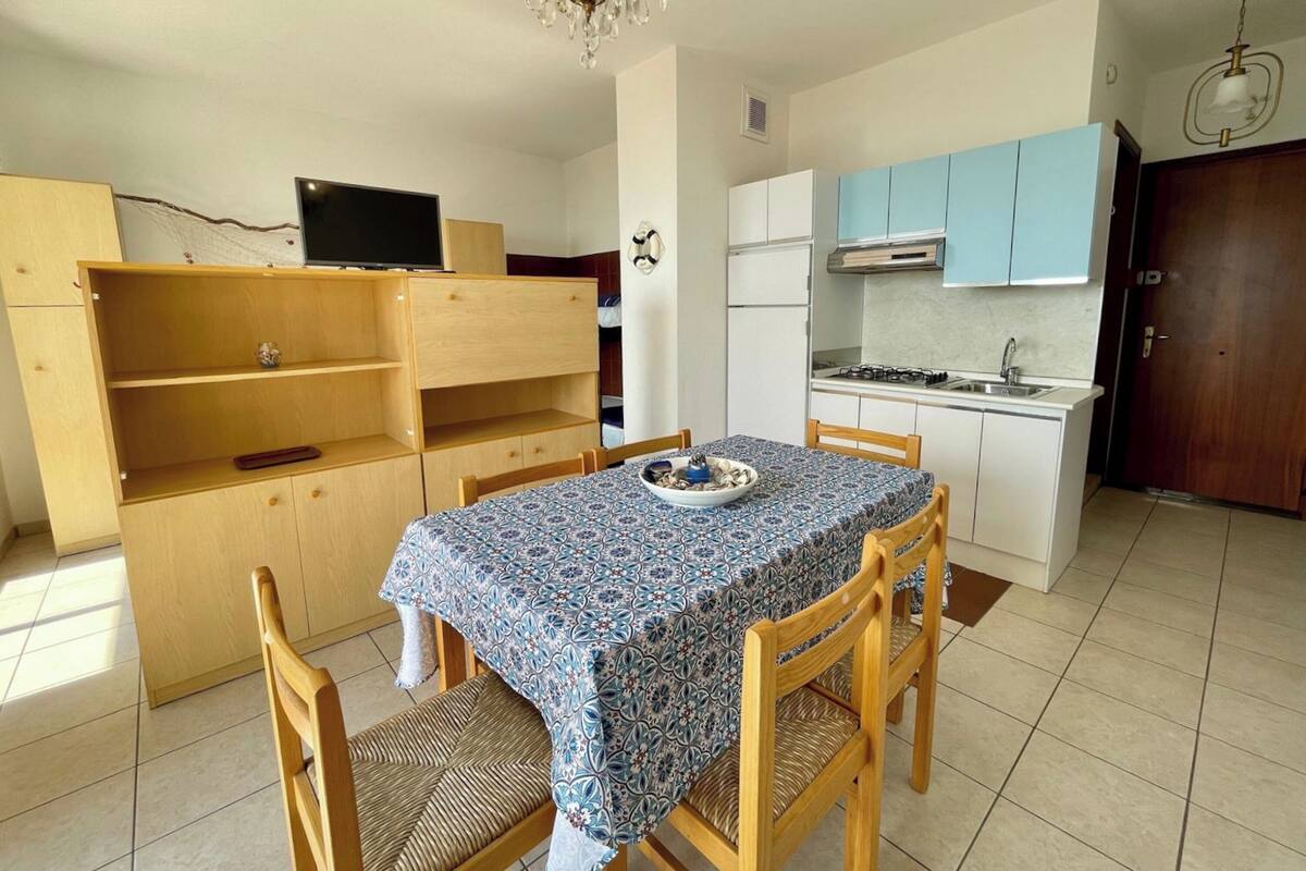 A compact kitchen with a dining table, chairs, and a TV on a stand.