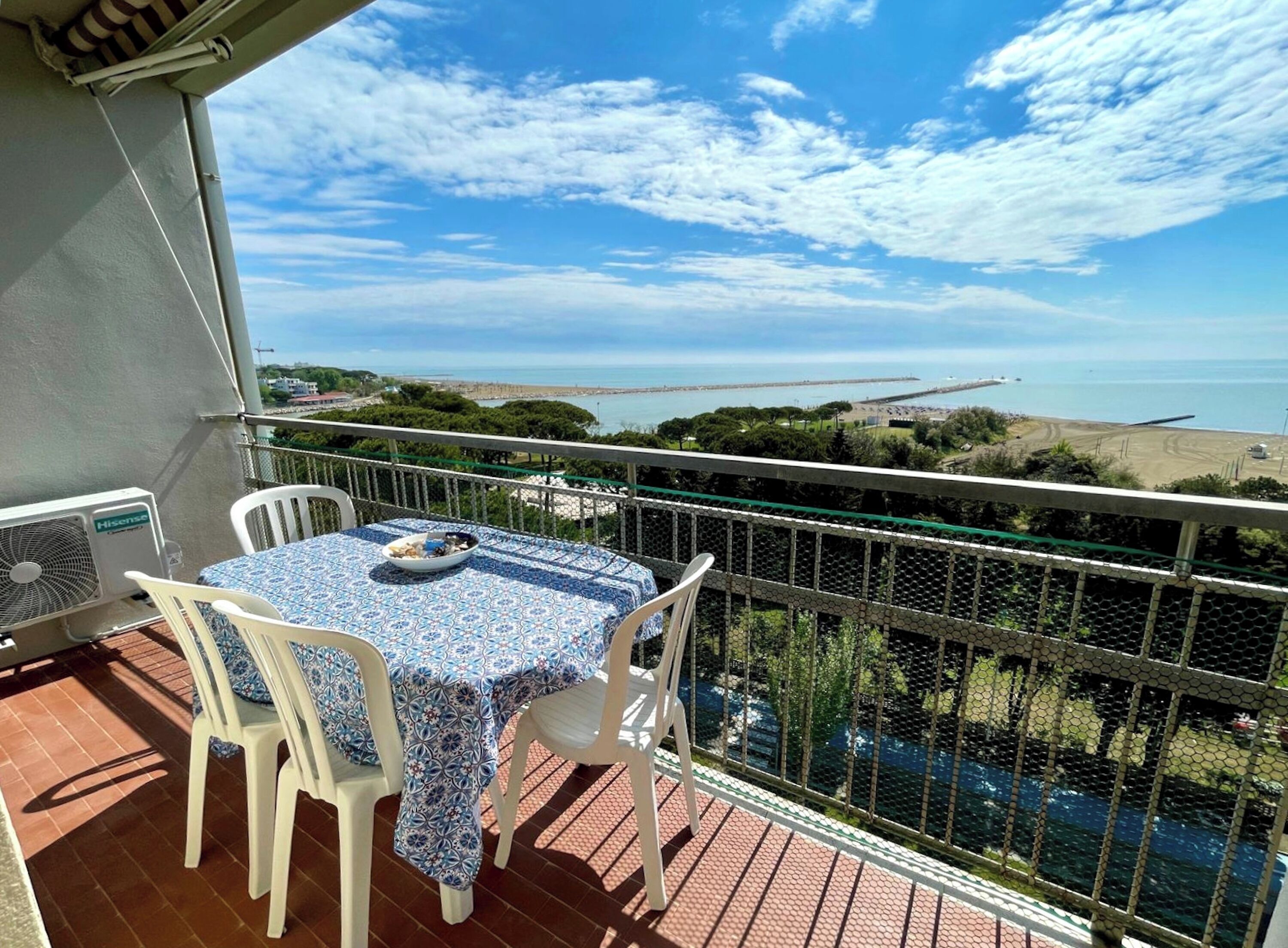 A balcony with a table and chairs, overlooking a coastal view.