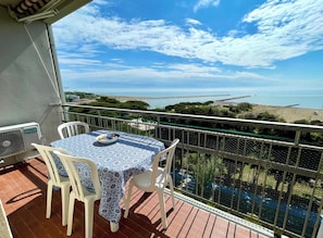 A balcony with a table and chairs, overlooking a coastal view. - Studio With Amazing Views-beahost (Caorle)