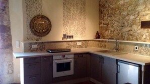 Una cocina con pared de piedra, un plato decorativo y un lavamanos moderno.