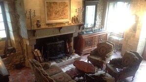Un salón tradicional con muebles antiguos, una chimenea y un tapiz grande.