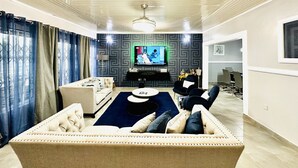A modern living room with a sofa, TV, and entertainment unit. - Nubian Villa-A Tropical Gem with Pool and Hot Tub (Adenta Municipality)