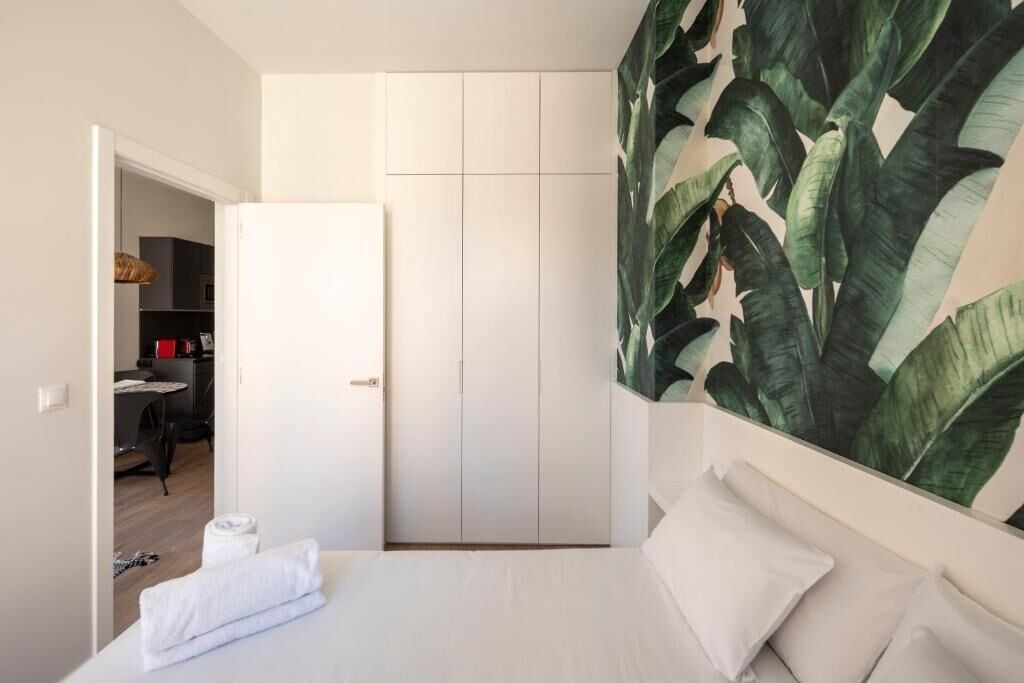 Un dormitori amb un llit, un armari i una pared de plantes gran.