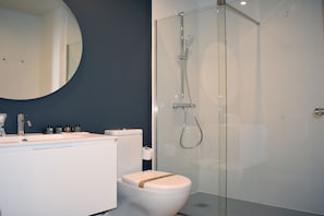 A modern bathroom with a glass-enclosed shower, a white sink, and a toilet. - Bow Homes by Como en Casa (Vigo)