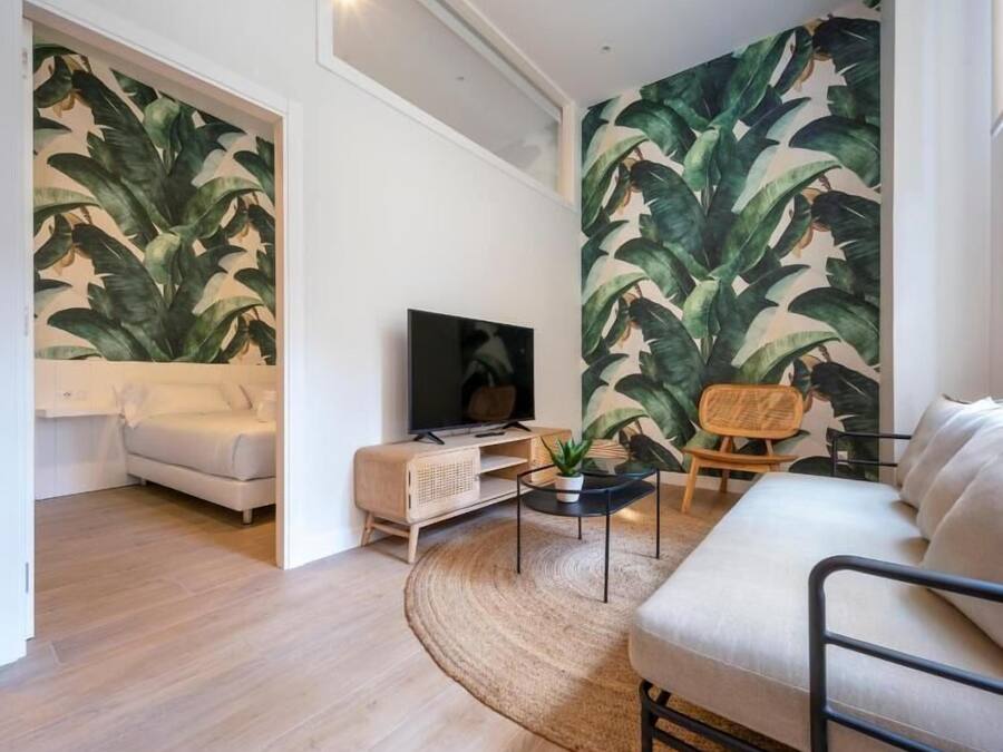 A modern living room with a large wall mural, a flat-screen TV, a sofa, a chair, and a coffee table.