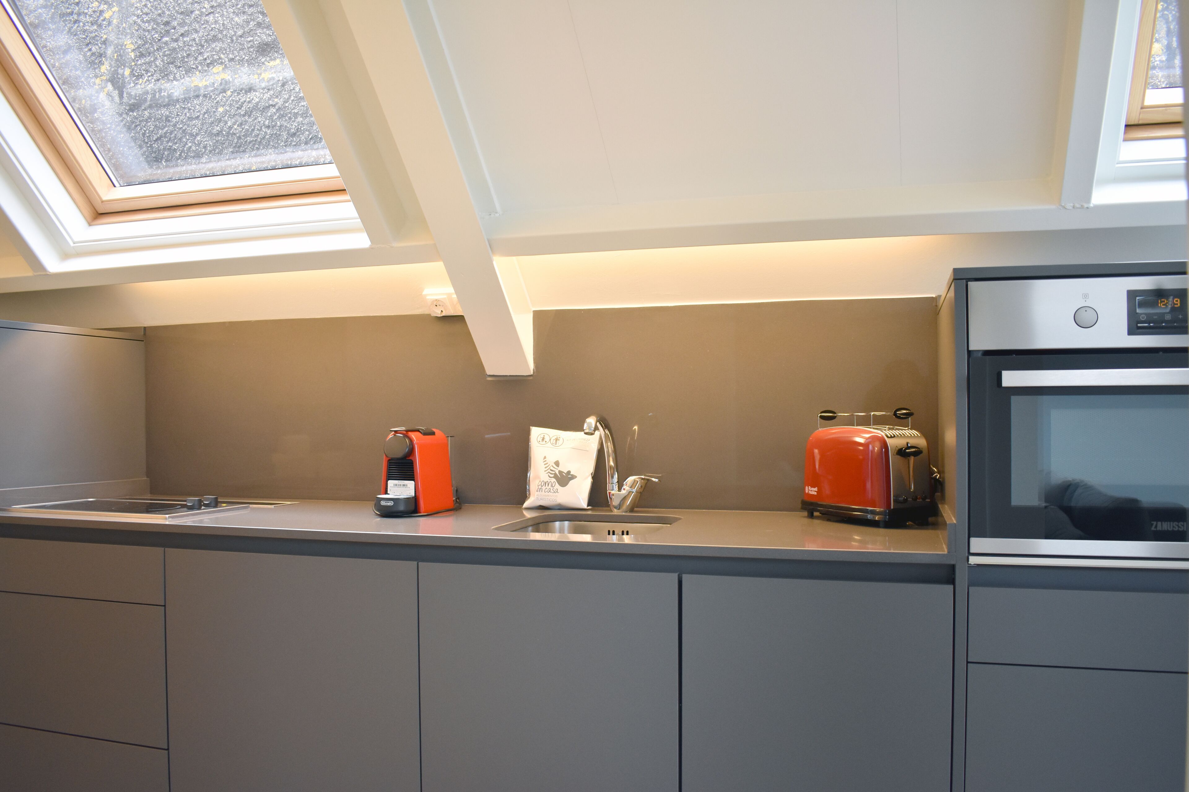 Een moderne keuken met een dakraam, een broodrooster, een waterkoker en een inbouwoven.