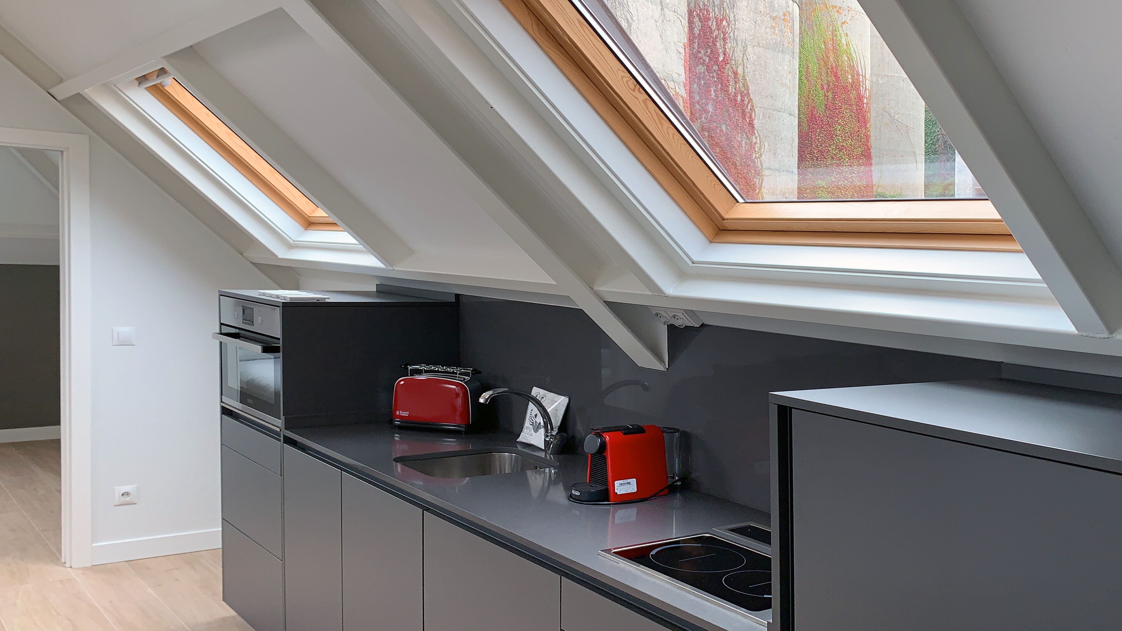 A modern kitchen with skylights, a red toaster, and a built-in oven.
