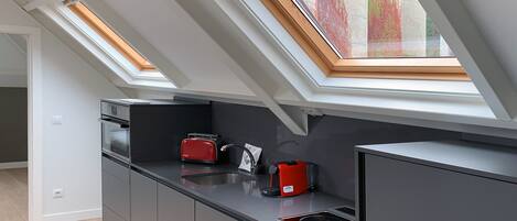 A modern kitchen with skylights, a red toaster, and a built-in oven.