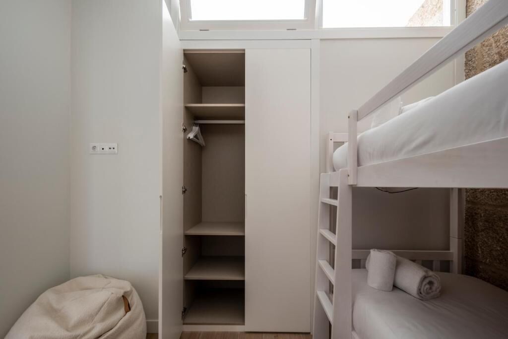A bunk bed with a white headboard and a small closet with open doors.