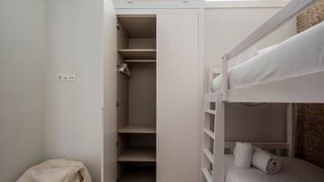 A bunk bed with a white headboard and a small closet with open doors.