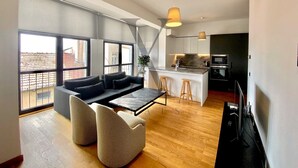A modern apartment with a living area featuring a sofa and chairs, a dining table, and a kitchen with a bar. - X Flats Taksim (Istanbul)
