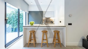 A modern kitchen with a large window, a marble countertop, and three wooden stools. - X Flats Taksim (Istanbul)