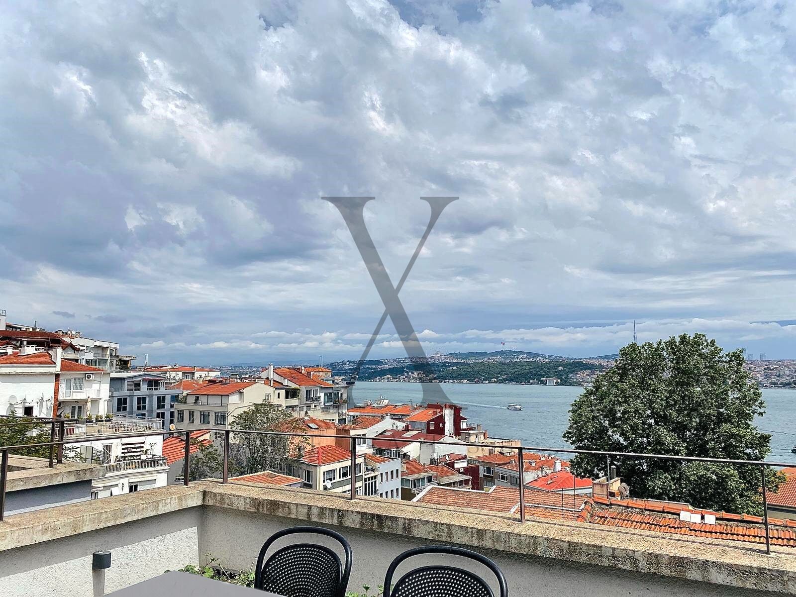 Una terraza en la azotea con vistas a un paisaje urbano y una masa de agua.