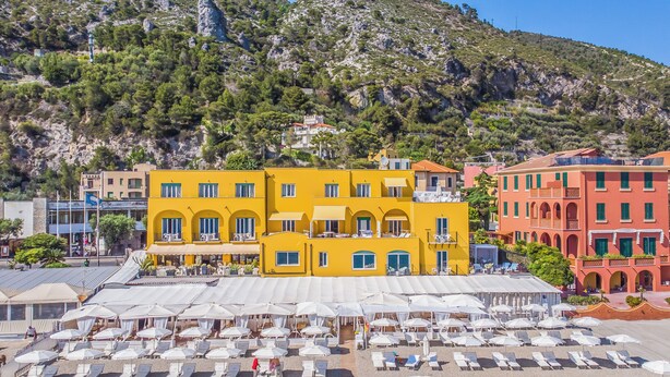 A beachside hotel with multiple floors, outdoor seating, and a mountainous backdrop. - Hotel Albatros Varigotti (Finale Ligure)