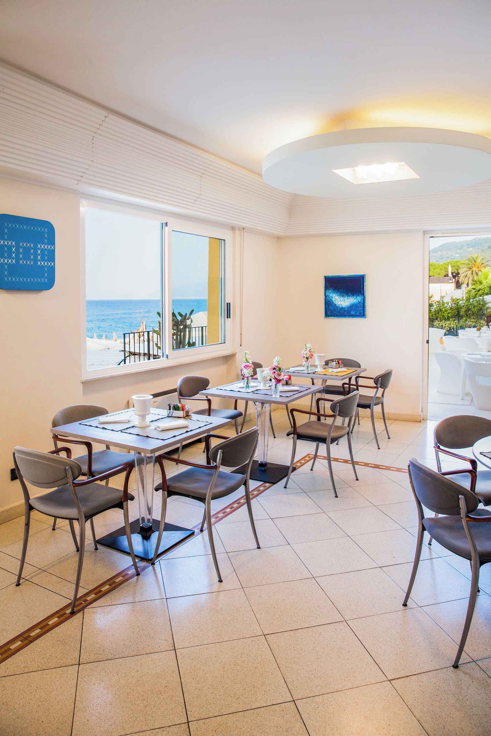 A dining area with a view of the sea, a round table, and chairs.