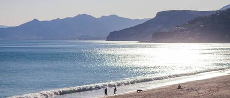 A beach with a clear view of the sea and distant mountains.