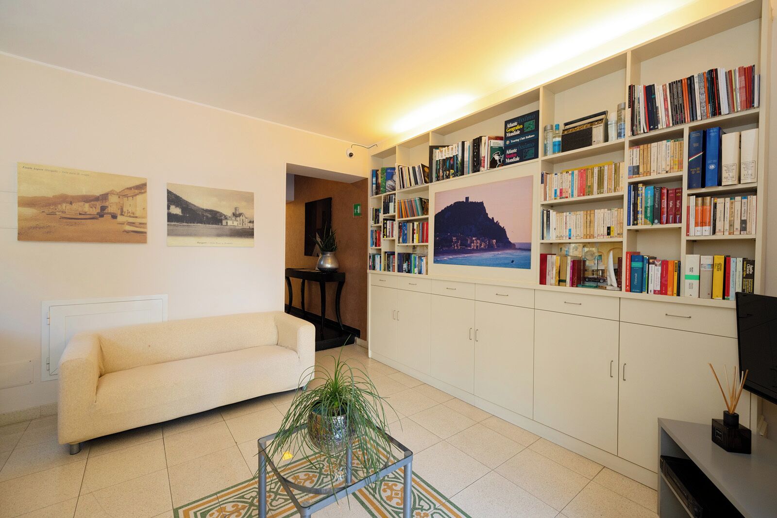 Un salon avec un canapé, une table basse, une bibliothèque et un tableau accroché au mur.
