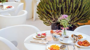 A table set with plates of food, a vase with flowers, and a cactus in the background. - Hotel Albatros Varigotti (Finale Ligure)