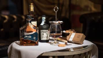 Un tavolo con una bottiglia di Flor de Caña, una bottiglia di tequila, un bicchiere di vino, un biscotto e una scatola di cioccolatini.