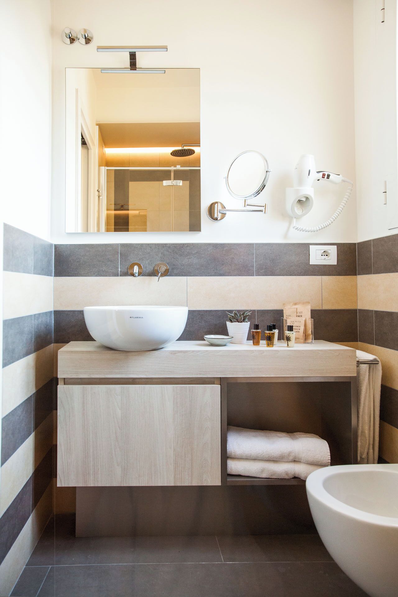 Uma casa de banho moderna com uma bacia grande, um espelho, um secador de cabelo e um porta-toalhas.